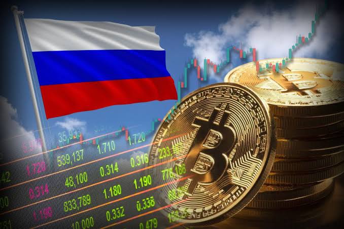 A Russian flag waves beside a stack of golden Bitcoin coins overlaid with colorful candlestick charts and trading figures (including values like 538,137, 1,710, and 1,720), visually symbolizing the launch of Russia's new regulated crypto trading framework. The juxtaposition of national flag and digital currency assets reflects the post's focus on Russia's newly legalized licensed crypto intermediaries while payment restrictions remain in place.