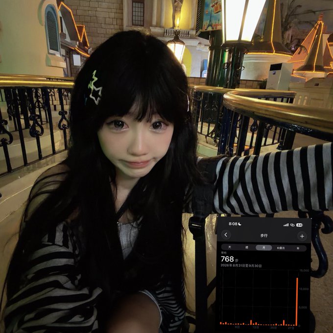 A young woman with long black hair and star hair clips poses for a selfie in a brightly lit indoor setting, with an inset showing a phone health app displaying 768 steps on 8月31日 (August 31st).