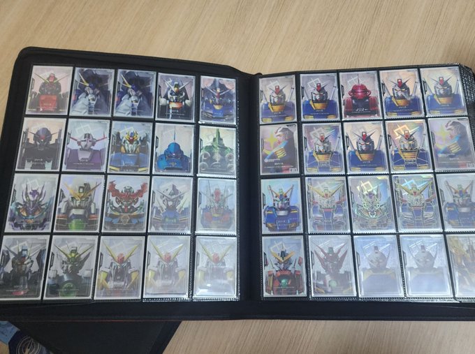 A collector's binder displays 40 Gundam GCG (Gundam Card Game) cards arranged across two pages, featuring various iconic mecha from the Gundam franchise. The post mentions the corrected social media handle @GUNDAM_GCG_JP, highlighting the user's growing collection and refined organization of their Gundam card collection.