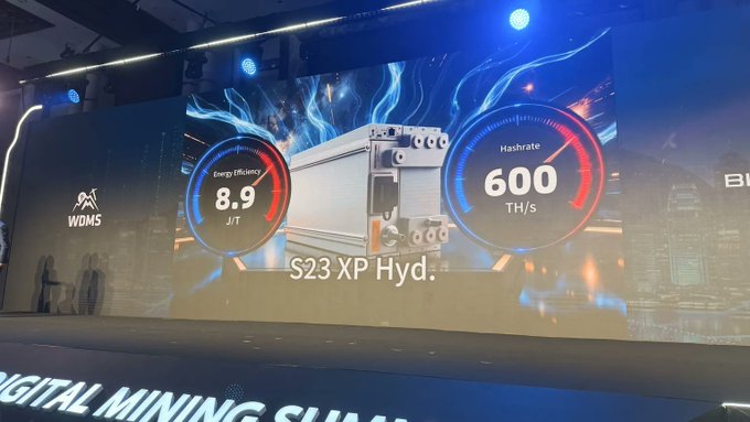 A presentation slide at the World Digital Mining Summit (WDMS) showcases BITMAIN's new Antminer S23 XP Hyd Bitcoin mining machine, featuring performance metrics of 600 TH/s hashrate and 8.9 J/T energy efficiency against a blue flame background.
