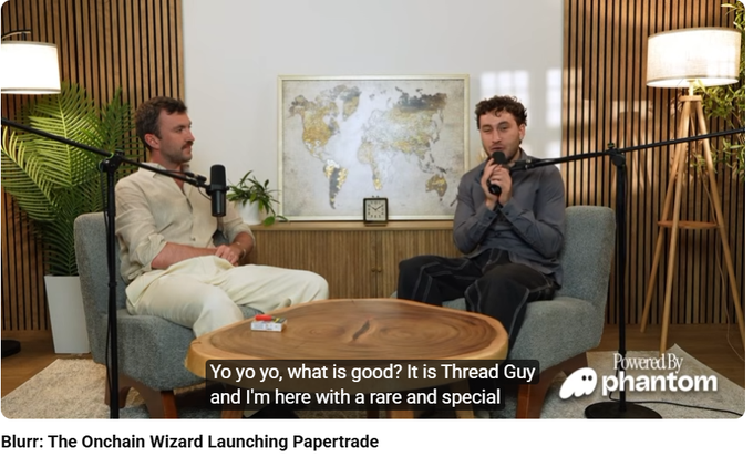Two men sit in armchairs with microphones in a podcast studio with a world map, captioned 'Blurr: The Onchain Wizard Launching Papertrade' and 'Yo yo yo, what is good? It is Thread Guy' with a 'Powered By Phantom' logo.