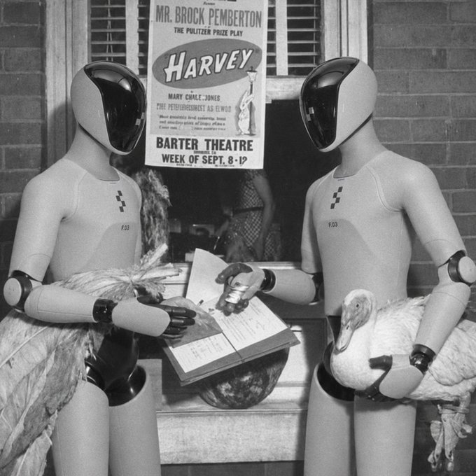 Two humanoid robots in white bodysuits labeled "F-01" and "F-03" stand at a Barter Theatre ticket window, with one consulting a binder while a poster behind them advertises the Pulitzer Prize play "Harvey" by Mr. Brock Pemberton starring Mary Coyle Jones, for the week of Sept. 8-17. The image humorously illustrates the post's theme of automation handling tedious tasks, as the robots methodically manage what was once mundane paperwork and transactions—now offloaded to AI agents via okx.ai.