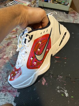 A hand holds up a custom-painted Nike Air Monarch sneaker featuring red mushroom designs, tying into the post's reference to "lawn mowing nfts" by showcasing a quirky, one-of-a-kind art piece reminiscent of collectible digital creations.
