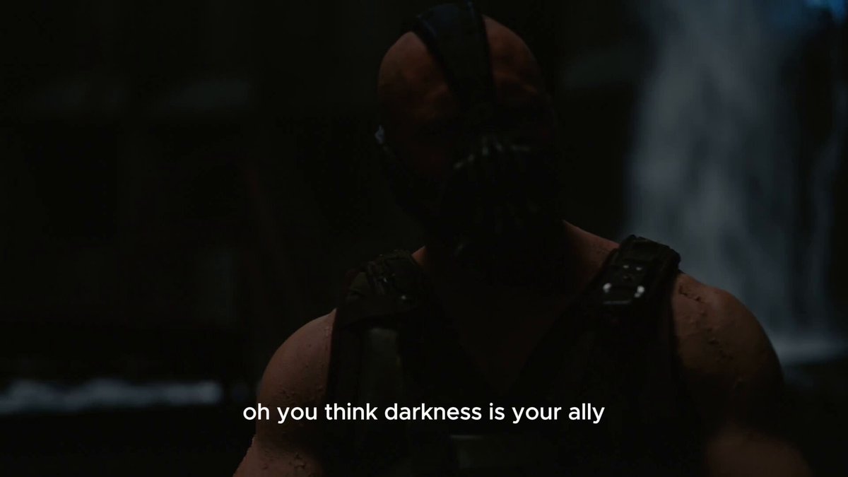 The image shows a man wearing a Batman mask, standing against a dark background with water falling from above. Below his head, there's text that reads "oh you think darkness is your ally", which seems to be a reference to the character Batman in the movie "The Dark Knight". The post also includes an image of the character himself and a caption about the character's role in the film.