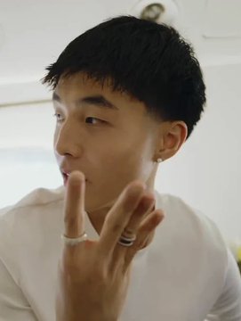A young man in a white shirt poses indoors with a two-finger hand gesture and rings. There is no visible text; the accompanying post concerns Kimchi removing Pump.fun from his bio and deleting his “LET’S WORK” reply.