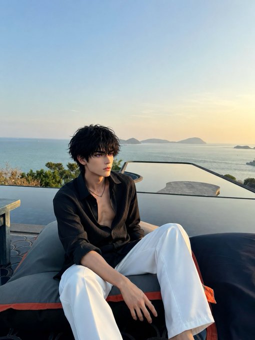 An anime-style illustration of a young man with dark hair wearing an unbuttoned black shirt and white pants, sitting outdoors with a scenic ocean view behind him.