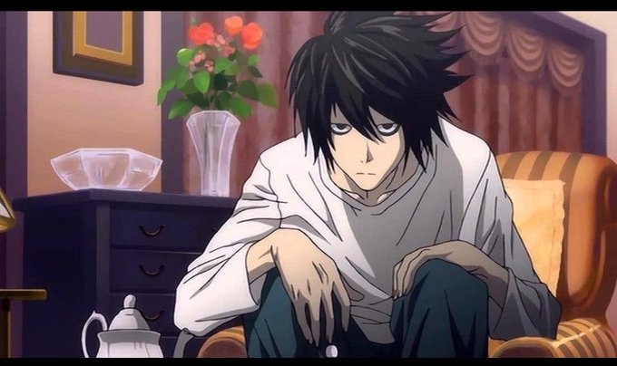 An anime character with messy black hair and a white shirt sits hunched over in a room with a vase of flowers, looking melancholic with drooping eyes.