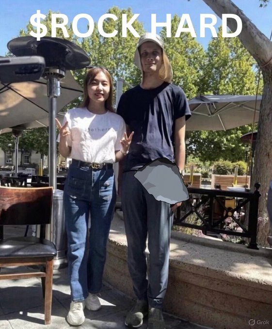 Two young people pose outdoors at a café with the text "$ROCK HARD" displayed at the top, while a rock graphic is superimposed over the man's groin area, humorously referencing his anatomy.