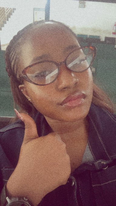 A young woman with glasses gives a thumbs up while taking a selfie, wearing a dark denim jacket. The image complements the post about being en route to the Solana Summit in Uyo, capturing her confident and ready-to-go vibe for the event.