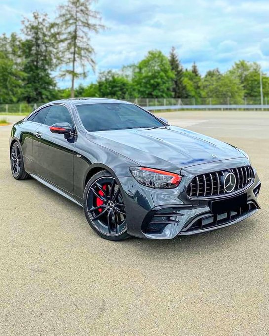 A sleek gray Mercedes-Benz coupe is parked on a paved lot, featuring a black grille, black alloy wheels, and red brake calipers.