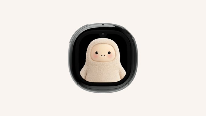 A small black device with a rounded square display showing a cute, smiling plush character with a hood, set against a white background.