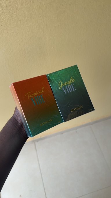A hand proudly displays two perfume boxes from Ravexan, labeled "Tropical Vibe" and "Jungle Vibe," showcasing the luxury purchases that made the 77k well spent.