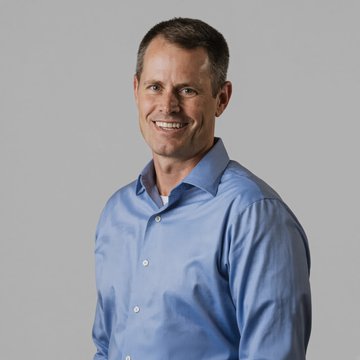A professional headshot shows a smiling man with short brown hair wearing a light blue button-down shirt against a gray background. The image accompanies news about Mike Colyer, the founding CEO of Foundry, stepping down from his position at the Bitcoin mining pool operator.