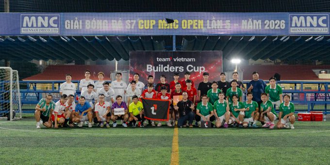 A group photo of soccer/football teams posing on a field at the 'MNC Open' tournament 2026 with a 'team vietnam Builders Cup' banner, featuring MNC branding.