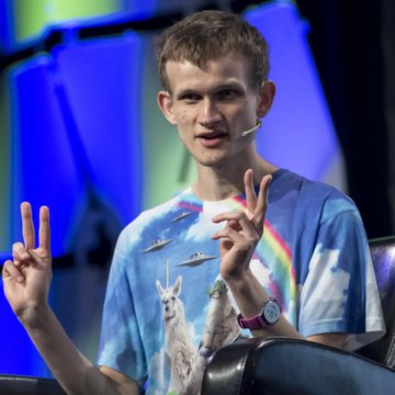 Vitalik Buterin, co-founder of Ethereum, gestures while speaking on stage in a colorful graphic t-shirt featuring llamas, sharks, and a rainbow, as he delivers his warning about AI potentially breaking Bitcoin's ECDSA cryptography within the next two years.