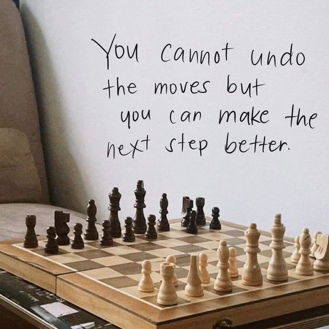 A handwritten motivational quote on a wall reads, "You cannot undo the moves but you can make the next step better." Below the quote sits a wooden chessboard with a game in mid-play, featuring various black and white pieces arranged across the checkered squares.