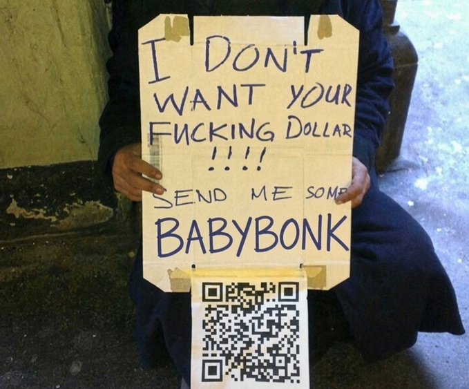 A person holding a handwritten cardboard sign that reads 'I DON'T WANT YOUR FUCKING DOLLAR !!!! SEND ME SOME BABYBONK' with a QR code displayed below.