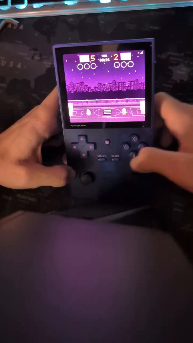 The image shows a person holding a small video game console, likely a Nintendo Wii, with their hands positioned over the screen as if they are about to play a game or interact with the device. The person appears to be focused on the game displayed on the screen and is ready for an exciting gaming session.
