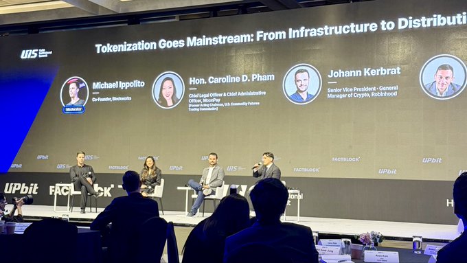 A panel discussion titled "Tokenization Goes Mainstream: From Infrastructure to Distribution" at the KBW (Keefe, Bruyette & Woods) conference features speakers Michael Ippolito (Co-Founder, Blockzero), Hon. Caroline D. Pham (Chief Legal Officer, U.S. Commodity Futures Trading Commission), and Johann Kerbrat (Senior Vice President - General Manager of Crypto, Robinhood), as seen on the large screen behind them while the panel addresses an audience. The image directly reflects the post's excitement about the discussion on tokenized equities and distribution with these three speakers.