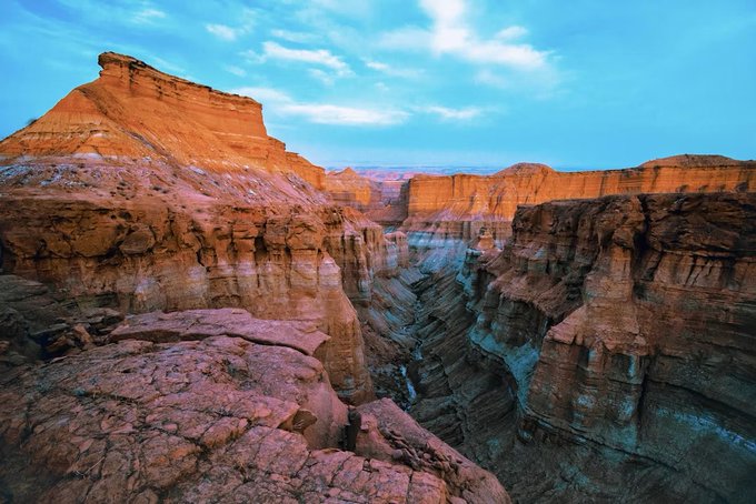 A rugged desert canyon with layered sandstone cliffs in warm red and orange tones under a soft blue sky, evoking a sense of ancient stillness that mirrors the artwork's title "Still Available When Oceans Slept." The timeless, weathered landscape complements the ethereal, contemplative nature of the NFT listing by Alijahanaraa on SuperRare.