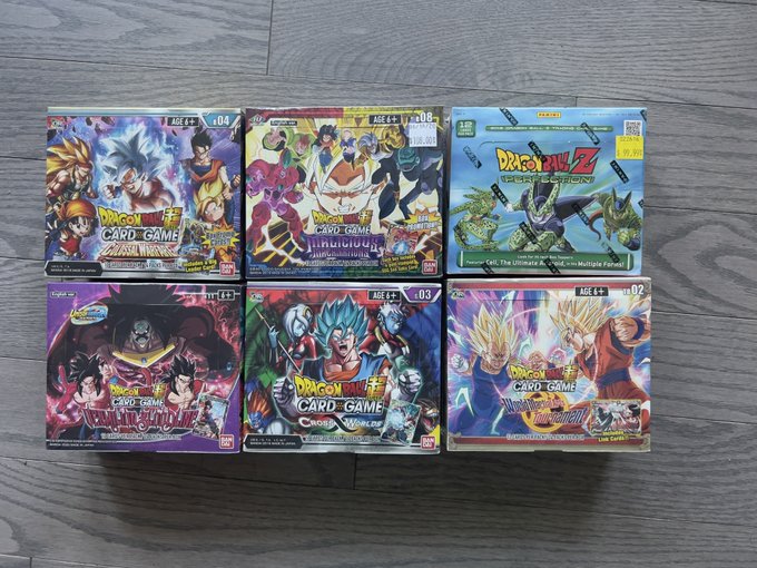 A collection of six sealed Dragon Ball Super Card Game booster boxes arranged on a wooden floor, including sets like Zenkai Series, Realm of the Gods, and Saiyan Legacy.
