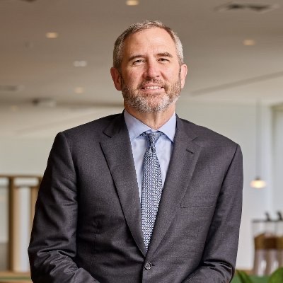 Brad Garlinghouse, CEO of Ripple, is shown smiling in a professional headshot wearing a dark suit and patterned blue tie, with the post expressing the author's dream of having him notice their social media content.