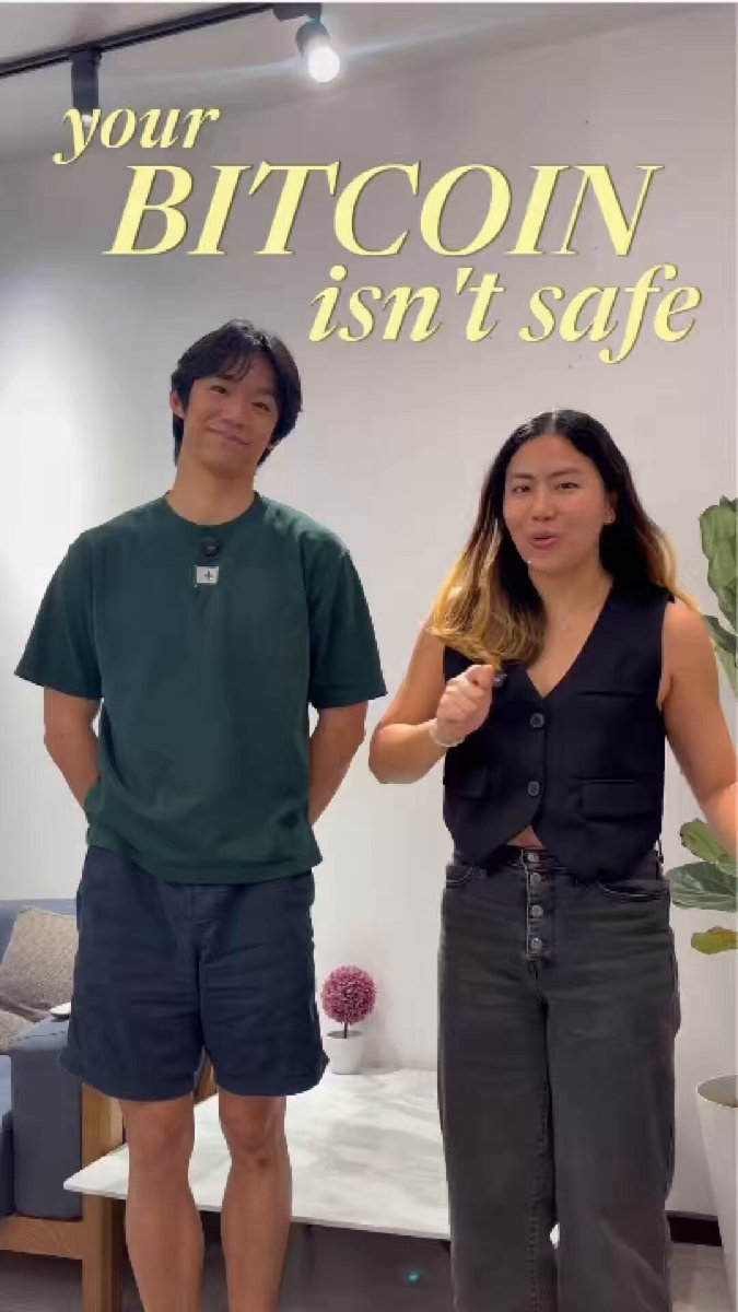 The image features a man and woman standing next to each other, both wearing black clothing. They are positioned against a white wall with a green plant behind them. The text "your bitcoin isn't safe i went around @ns asking people if their crypto is safe" is displayed above the couple in the photo.