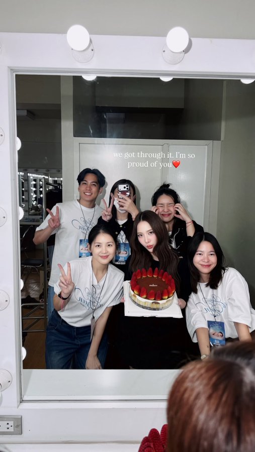 A group of six friends poses happily behind a mirror selfie, gathered around a strawberry-topped chocolate cake with the caption "we got through it. I'm so proud of you ❤️" displayed above them. The cheerful gathering captures a celebratory moment that reflects the post's message about Solenso being "awesome."