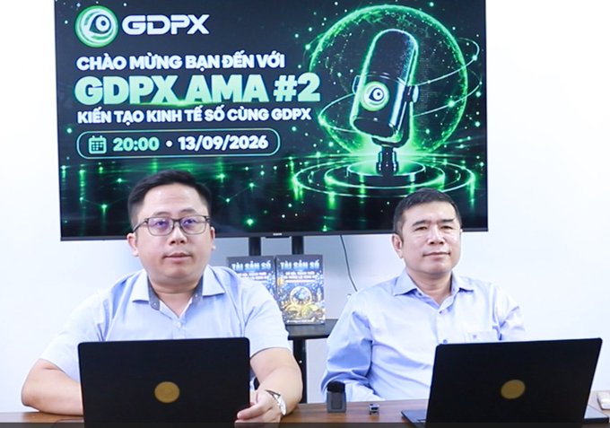 Two men in blue shirts sit at a table with laptops in front of a screen displaying "GDPX" and "GDPX AMA #2 KIẾN TẠO KINH TẾ SỐ CÙNG GDPX" with a scheduled time of 20:00 on 13/09/2026.