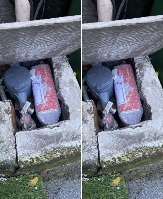 The stereo image shows a metal utility box with its hinged cover partially ajar, concealing a watermeter assembly nestled inside a concrete recess—the top portion clearly marked with "STOP" and an arrow, while the circular dial reads "Itron." The delivery person's clever concealment aligns with the post's humor: hiding packages so thoroughly that even the courier struggles to retrieve them.