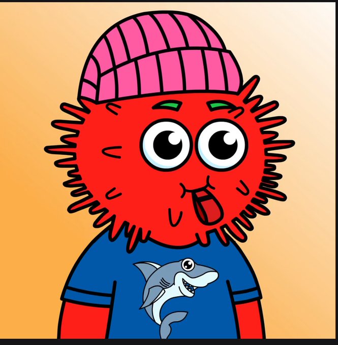 A cartoon character with a fuzzy red face, large eyes, sticking its tongue out, wearing a pink beanie and a blue t-shirt with a shark on it.