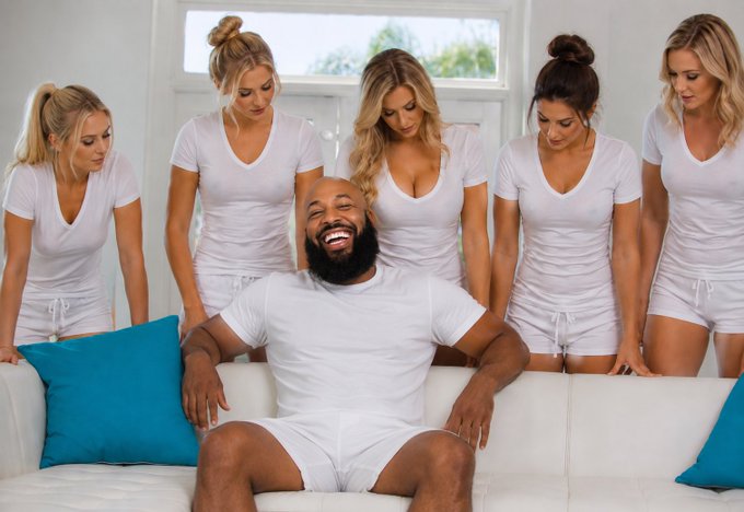 A bearded man sits on a white couch laughing, surrounded by five women in white outfits, suggesting a playful "guy's dream" scene that fits the casual, tongue-in-cheek tone of the Solana giveaway post promising a quick 180-minute random draw.