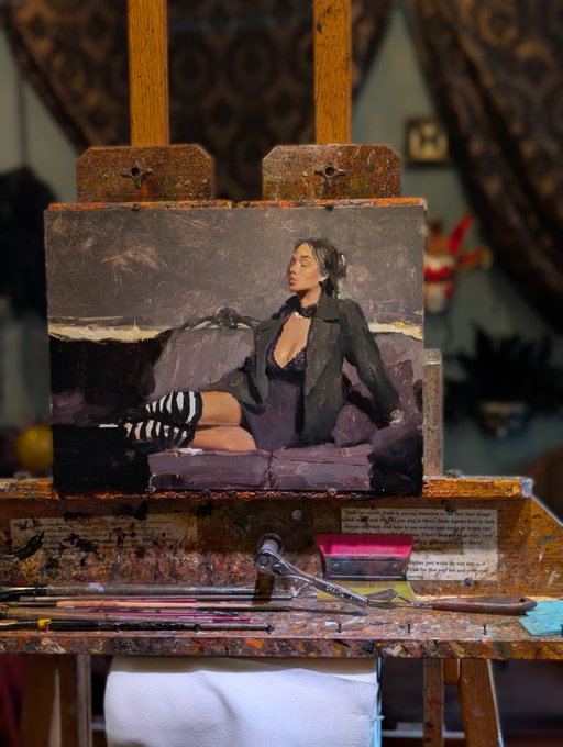 A painting on an easel depicting a woman in a black jacket and striped stockings sitting on a purple sofa, with paintbrushes and palette knives resting below.