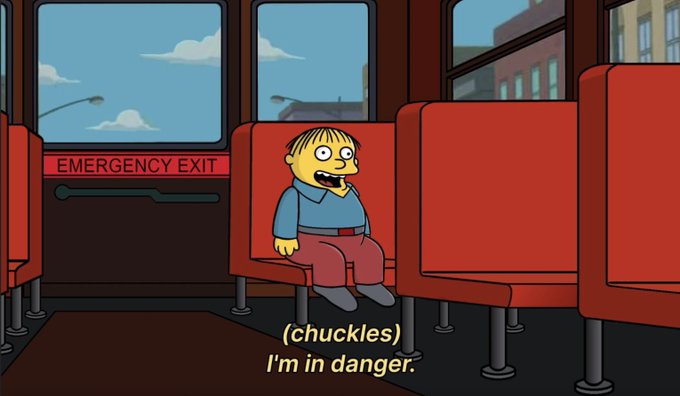 Ralph Wiggum from The Simpsons sits alone on a red bus seat next to an "EMERGENCY EXIT" door, with subtitles reading "(chuckles) I'm in danger."