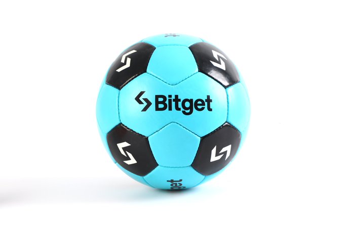 The image features a blue soccer ball with black and white accents, which appears to be a Bitget branded soccer ball. The ball has a logo on its surface that reads "bitget" along with the company's name. It is positioned against a plain white background, making it stand out prominently in the photo.
