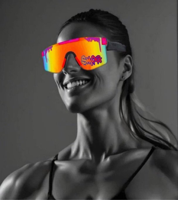 A black-and-white photo of a smiling woman whose sunglasses have been colorized to show a rainbow reflective lens with graffiti-style tags.