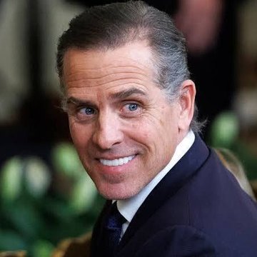 A middle-aged man with dark slicked-back hair and blue eyes smiles warmly at the camera while wearing a dark suit and white shirt, appearing relaxed in what looks like an outdoor or garden setting. The accompanying post connects the image to Hunter Biden's announcement of a new $LAPTOP memecoin, referencing the infamous laptop controversy from the 2020 election cycle.