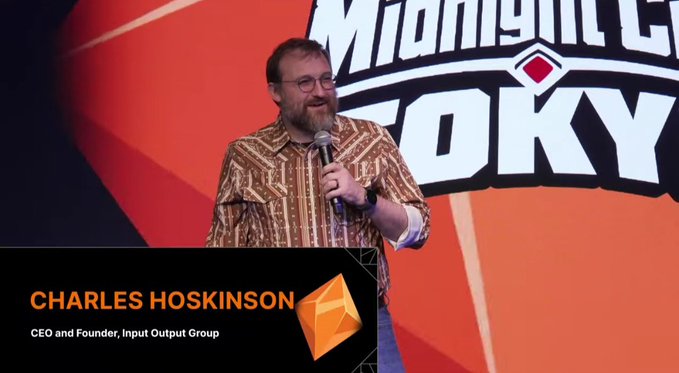 Charles Hoskinson, identified as CEO and Founder of Input Output Group, speaking into a microphone while wearing a patterned brown shirt at the 'Midnight TOKYO' event.