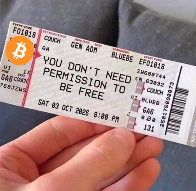 A hand holds a ticket dated "SAT 03 OCT 2026 8:00 PM" bearing the bold message "YOU DON'T NEED PERMISSION TO BE FREE," overlaid with a Bitcoin (₿) logo. The image ties to the "Wake up anon" post by symbolizing financial and personal liberation through Bitcoin's permissionless, decentralized ethos—encouraging the viewer to break free from traditional gatekeepers, both monetary and societal.