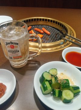 iced tea, beer mug with "JIM BEAM" label, and a grill with hot dogs are arranged on a wooden table.