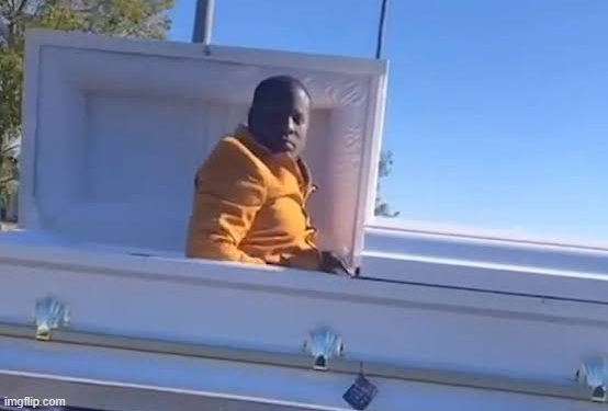 A young man in a bright orange hoodie sits in what appears to be an open attic window, looking down at the viewer with a defeated, glum expression against a clear blue sky. The image humorously illustrates the post's joke about people who "FOMO bought Bitcoin at $102k today," capturing the misery of investors who bought at the peak and are now stuck watching their losses from above.