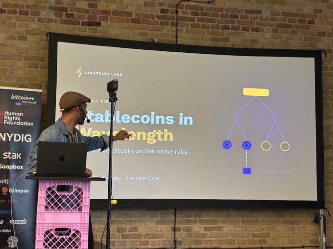 A man giving a presentation titled 'Stablecoins in Wavelength' at an event sponsored by Lightning Labs, dated 2 October 2026.