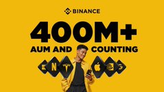 The image is an advertisement for Binance Stocks featuring an image of a smiling man using his phone while standing under a "Binance" banner. In the background, there are different symbols representing various cryptocurrencies such as Bitcoin, Ethereum, Ripple, Litecoin, and others. The main message from the post is about supporting and fostering growth in the cryptocurrency community and building something together with everyone's participation.