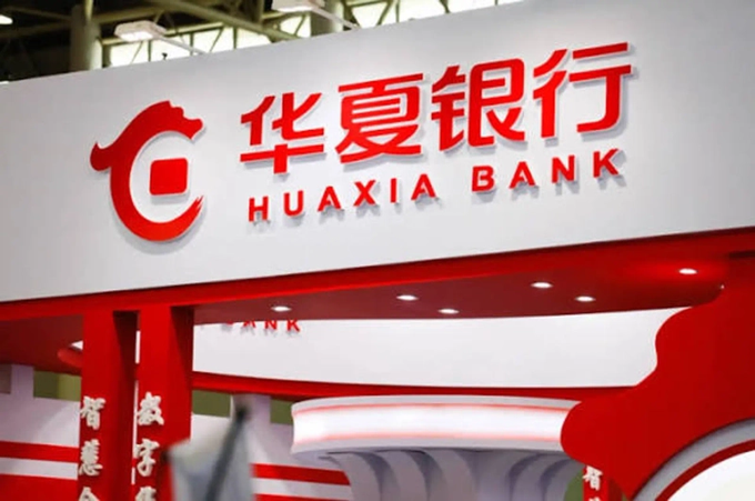 The image shows a large sign for "华夏银行 HUAXIA BANK" in red and white, likely at an exhibition or corporate display. The accompanying Korean text discusses how the spread of regulated stablecoins and tokenized funds in Hong Kong could expand blockchain finance and RWA markets, potentially increasing demand for Bitcoin, though it notes that increased stablecoin usage does not necessarily translate directly into Bitcoin purchases. The Huaxia Bank signage appears relevant as it represents traditional Chinese banking, which intersects with the broader theme of digital asset regulation and financial innovation discussed in the post.