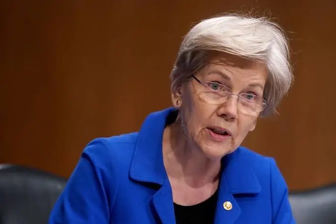 Senator Elizabeth Warren, wearing a blue blazer and glasses, is shown speaking during what appears to be a Senate hearing, her expression serious and focused. The image likely accompanies the post criticizing her stance, as she is a known advocate for stricter cryptocurrency regulation, with the poster sarcastically thanking her for a Bitcoin price dip following her anti-crypto remarks.
