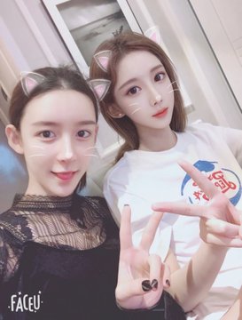 Two women pose closely for a selfie, both wearing playful cat-ear filters and making peace signs, with the "FACEU" app logo visible in the corner. The image relates to the post's theme of gender transition, as the author reminisces about a former business partner who underwent gender transition, suggesting the photo may depict them.