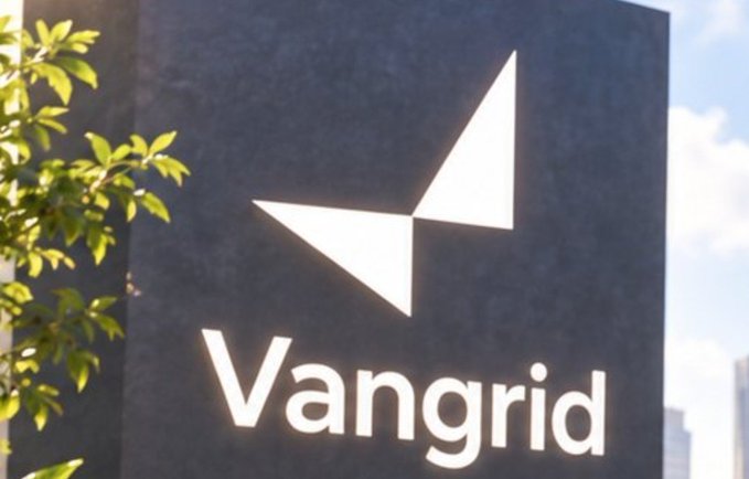 A photo of a dark outdoor sign displaying the "Vangrid" logo (a white geometric V/triangle design) with green tree leaves and a blue sky visible in the background.