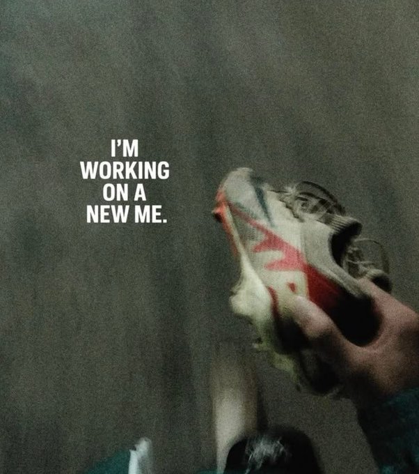 A dark, grainy image of a person wearing a bandana covering their face with red 'X' marks, accompanied by the text 'I'M WORKING ON A NEW ME.'