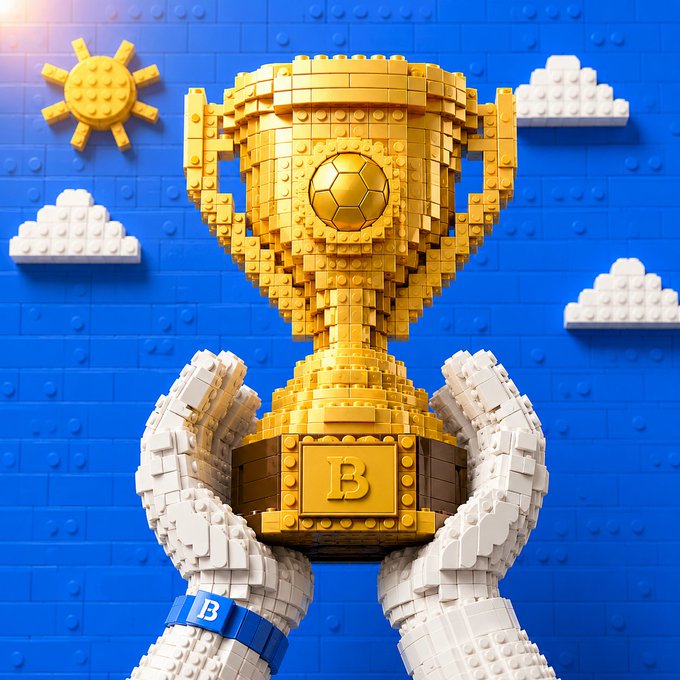 A golden LEGO-style trophy with a soccer ball emblem and the letter "B" is held aloft by white LEGO hands against a bright blue sky with a sun and clouds. The image visually reinforces the post's message of "building" toward success, symbolizing the Biconomy community constructing milestones block by block in the Web3 and crypto space.