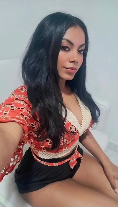 The image shows a woman with long, dark wavy hair posing in a selfie-style photo, wearing a red crochet top over a white bralette and black shorts. The casual, relaxed pose complements the friendly good night message to followers, suggesting an end-of-day social media post.